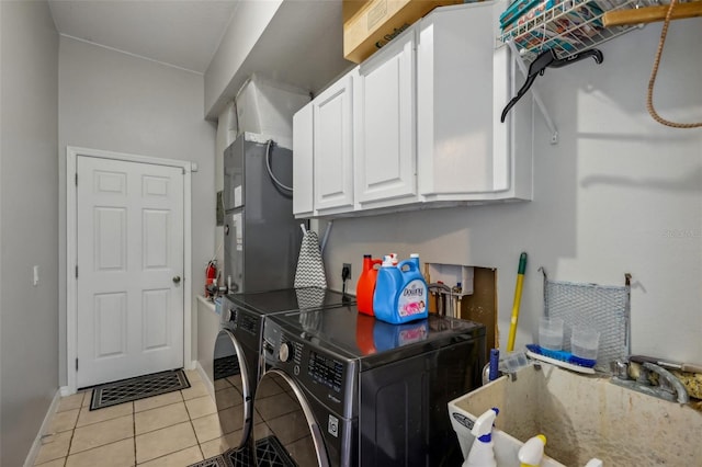 clothes washing area featuring light tile patterned flooring, sink, cabinets, heating unit, and washer and dryer