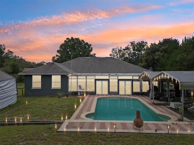 pool at dusk featuring a patio area and a yard