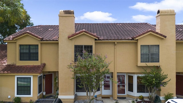 view of front of property with a tile roof, stucco siding, and a chimney