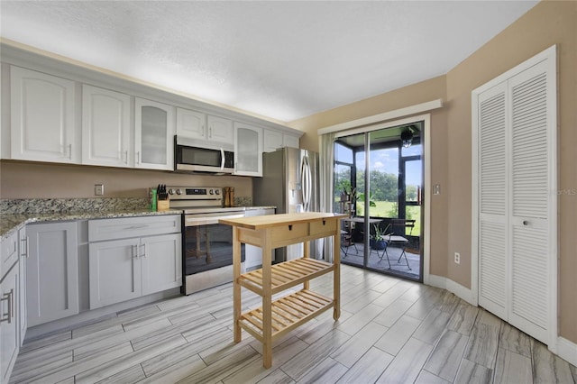 kitchen with appliances with stainless steel finishes, white cabinets, and light stone countertops