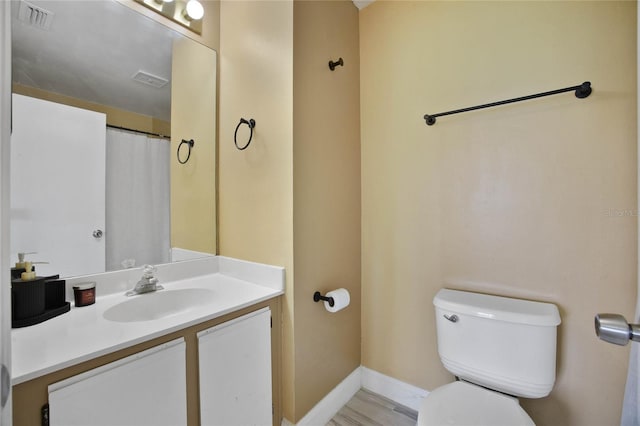 bathroom with vanity, toilet, baseboards, and visible vents