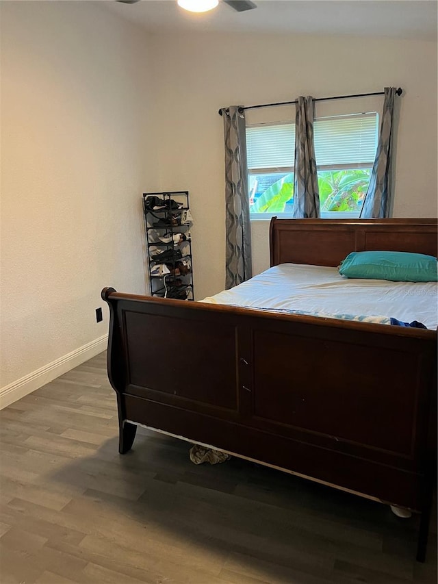 bedroom with baseboards, vaulted ceiling, and wood finished floors