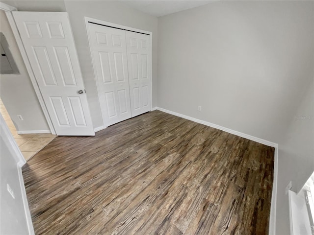 unfurnished bedroom featuring hardwood / wood-style flooring, electric panel, and a closet