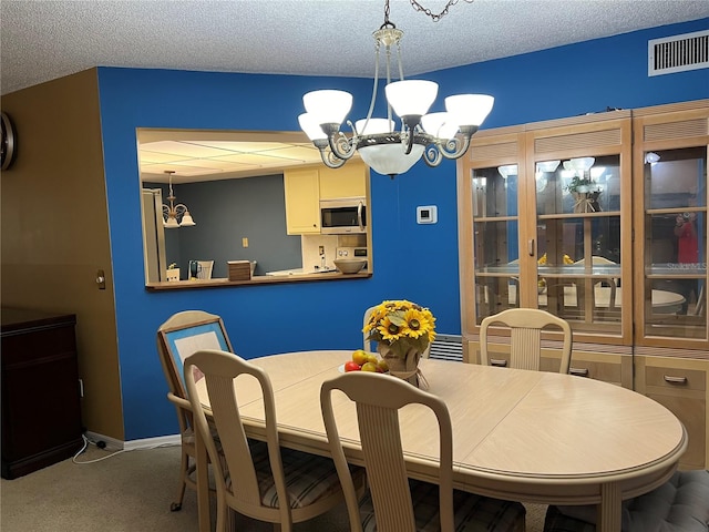 carpeted dining area featuring a textured ceiling and a notable chandelier