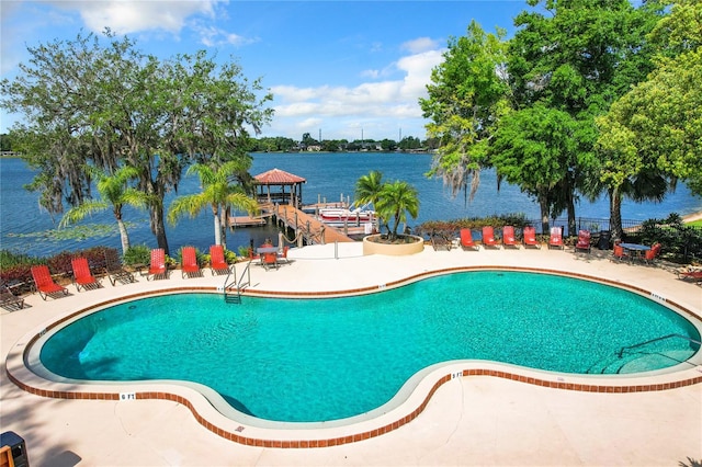 view of pool featuring a patio area, a boat dock, and a water view