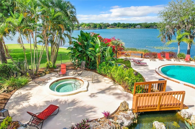 view of pool featuring a hot tub, a water view, and a patio area