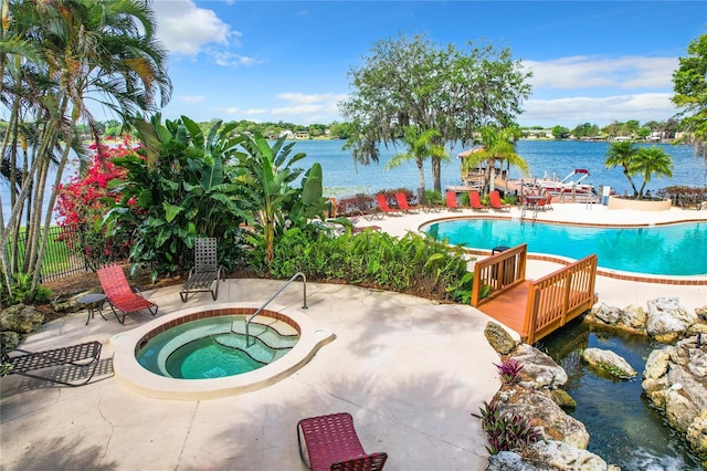 view of swimming pool with a patio area, a community hot tub, and a water view