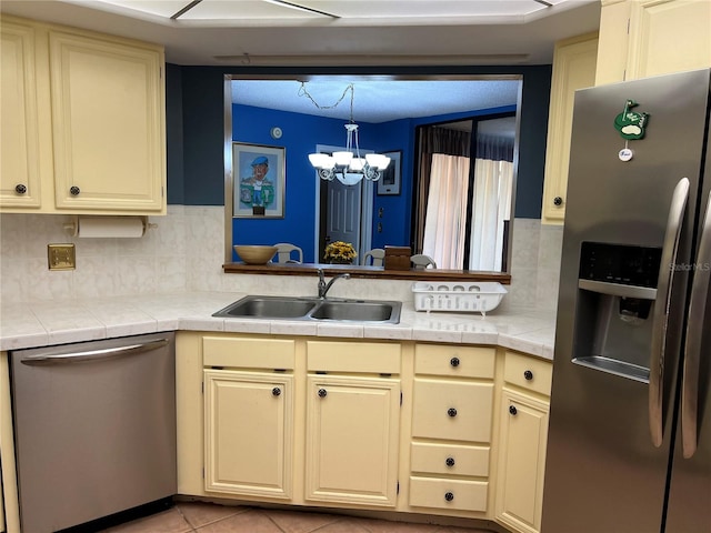 kitchen featuring appliances with stainless steel finishes, tasteful backsplash, sink, tile counters, and a notable chandelier