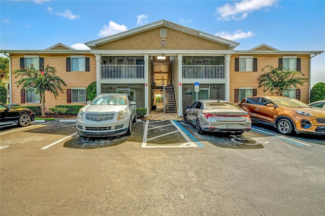 view of property featuring uncovered parking and stairway