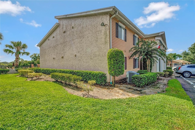 view of property exterior with cooling unit, a lawn, and stucco siding