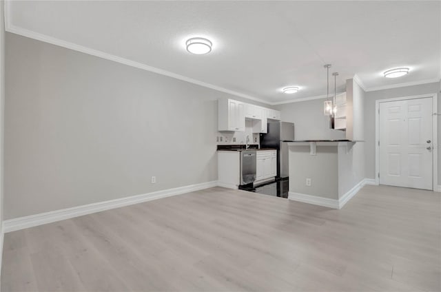 kitchen featuring a peninsula, a sink, white cabinetry, dark countertops, and decorative light fixtures