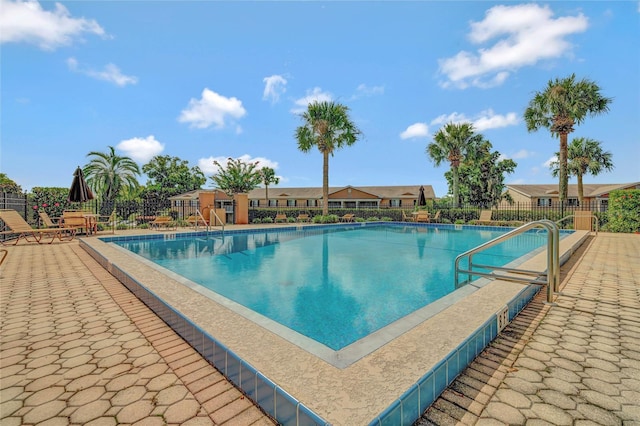 community pool with a patio area, a residential view, and fence