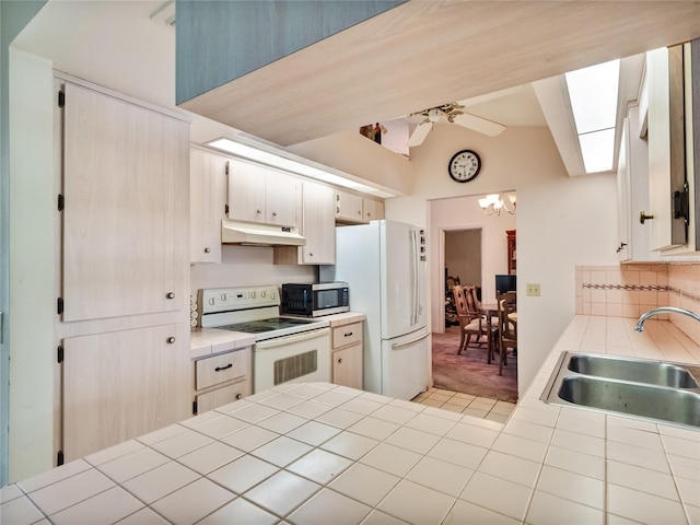 kitchen featuring ceiling fan, white appliances, sink, tile counters, and lofted ceiling