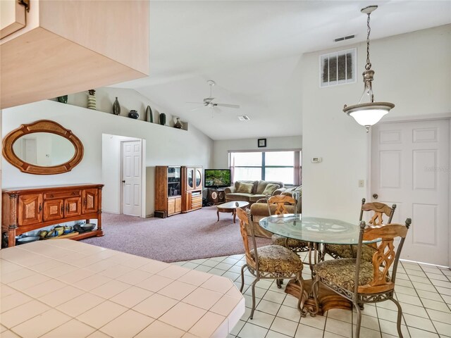 tiled dining area with ceiling fan and high vaulted ceiling