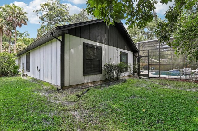 view of side of home with glass enclosure, a fenced in pool, and a yard