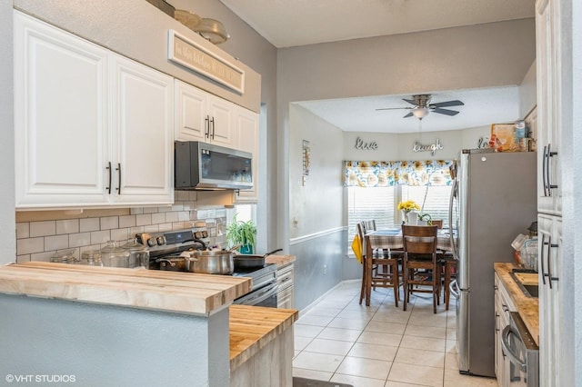 kitchen with white cabinetry, light tile patterned flooring, stainless steel appliances, and wood counters