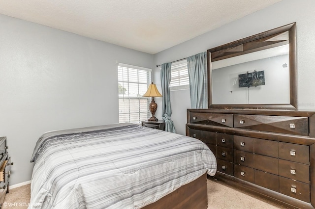 bedroom with baseboards, light colored carpet, and a textured ceiling