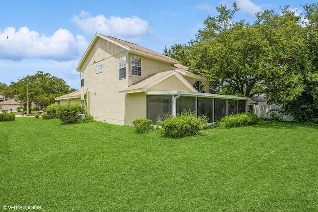 back of property featuring a sunroom and a lawn