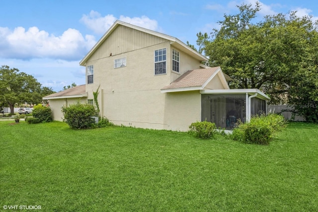 view of side of property featuring a sunroom, a shingled roof, and a lawn