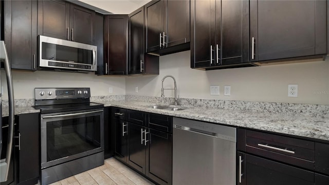 kitchen featuring light stone countertops, dark brown cabinetry, stainless steel appliances, and sink