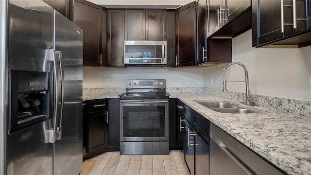 kitchen featuring dark brown cabinetry, light stone counters, sink, and appliances with stainless steel finishes