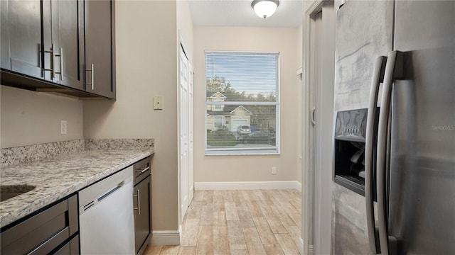 kitchen featuring light stone countertops, dishwasher, stainless steel fridge with ice dispenser, dark brown cabinets, and light wood-type flooring