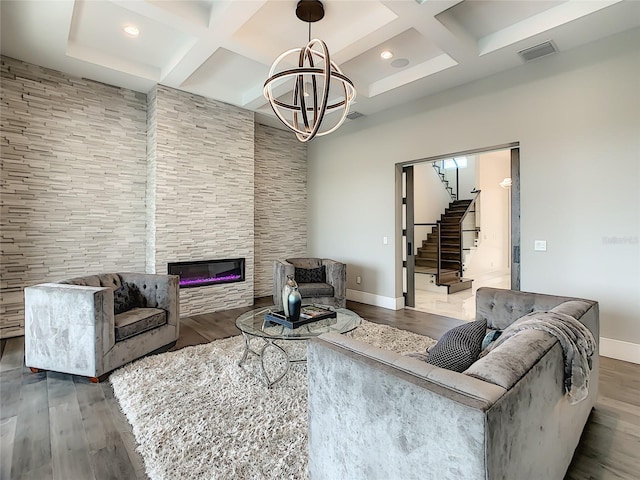 living room featuring dark hardwood / wood-style flooring, a stone fireplace, and coffered ceiling