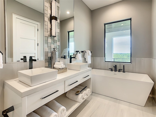 bathroom with double sink vanity and a tub to relax in