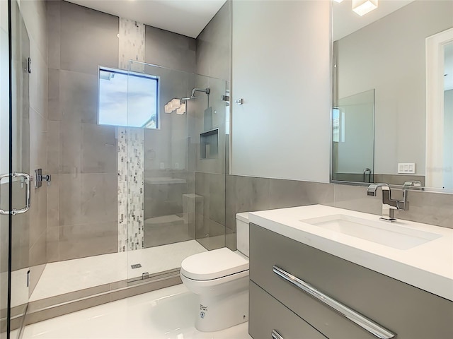 bathroom featuring a shower with shower door, tile walls, toilet, and vanity