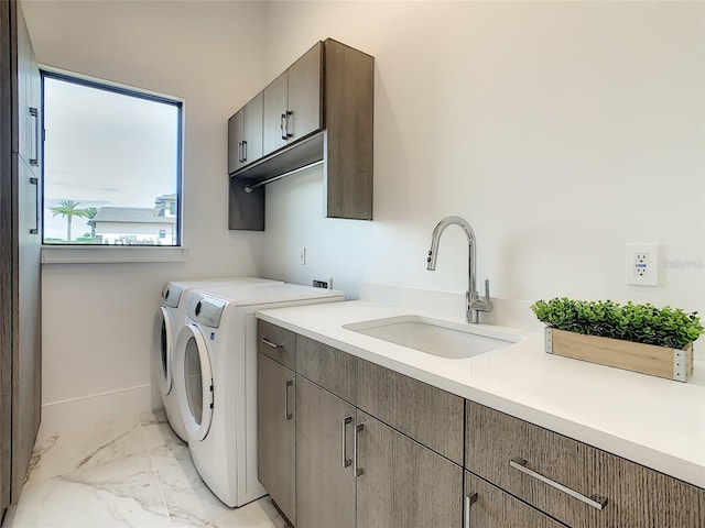 clothes washing area featuring sink, light tile patterned floors, separate washer and dryer, and cabinets