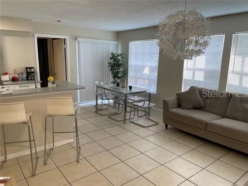 1073 S Hiawassee Rd Unit 1018, Orlando, FL 32835 - living room with light tile patterned floors, a textured ceiling, and baseboards