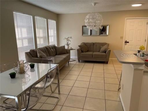 1073 S Hiawassee Rd Unit 1018, Orlando, FL 32835 - living area featuring light tile patterned floors, a chandelier, and baseboards