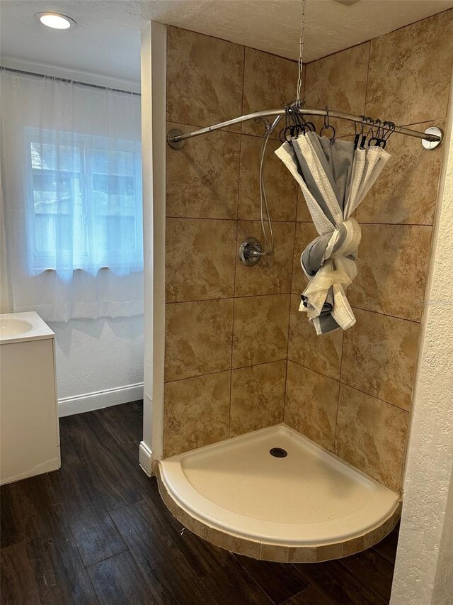 bathroom featuring a textured ceiling, tiled shower, vanity, and hardwood / wood-style flooring