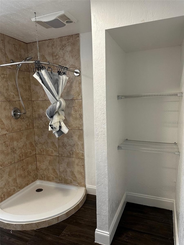 bathroom with hardwood / wood-style flooring, a textured ceiling, and tiled shower