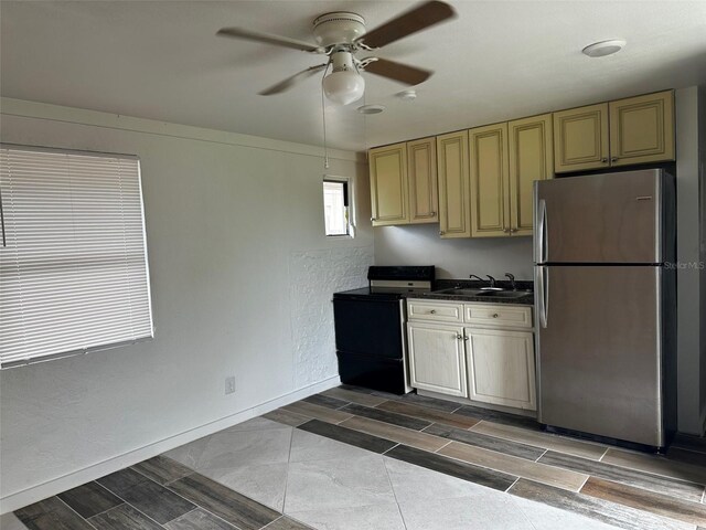 kitchen with stainless steel refrigerator, sink, cream cabinets, electric range oven, and ceiling fan