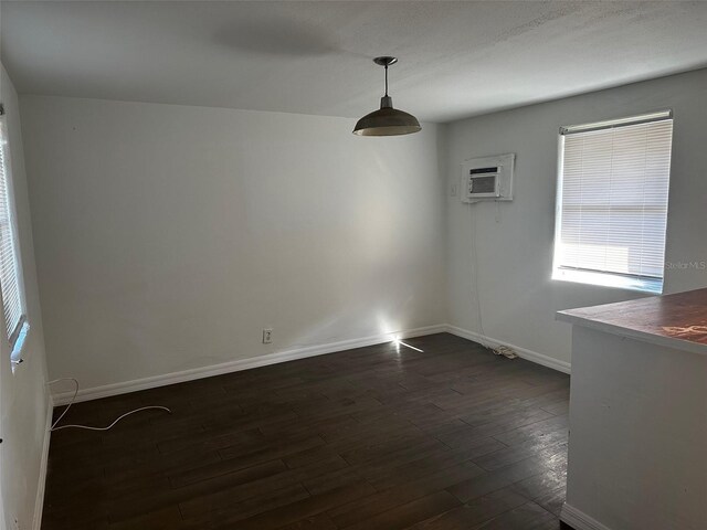 unfurnished room with dark hardwood / wood-style floors and a wall mounted air conditioner