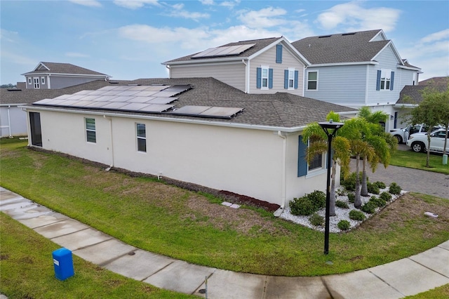 view of side of property featuring a lawn and solar panels