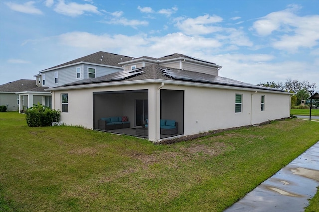 rear view of property featuring a lawn and solar panels