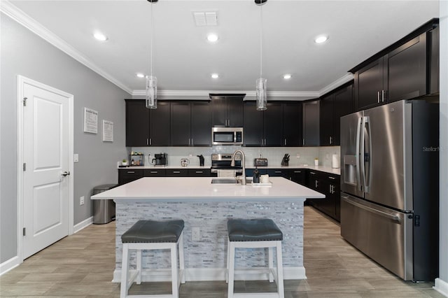 kitchen with stainless steel appliances, an island with sink, sink, and pendant lighting