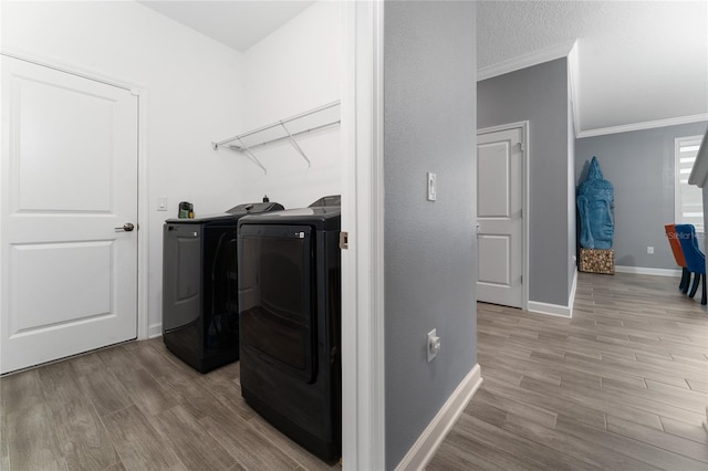 laundry room with ornamental molding, washer and dryer, and light wood-type flooring