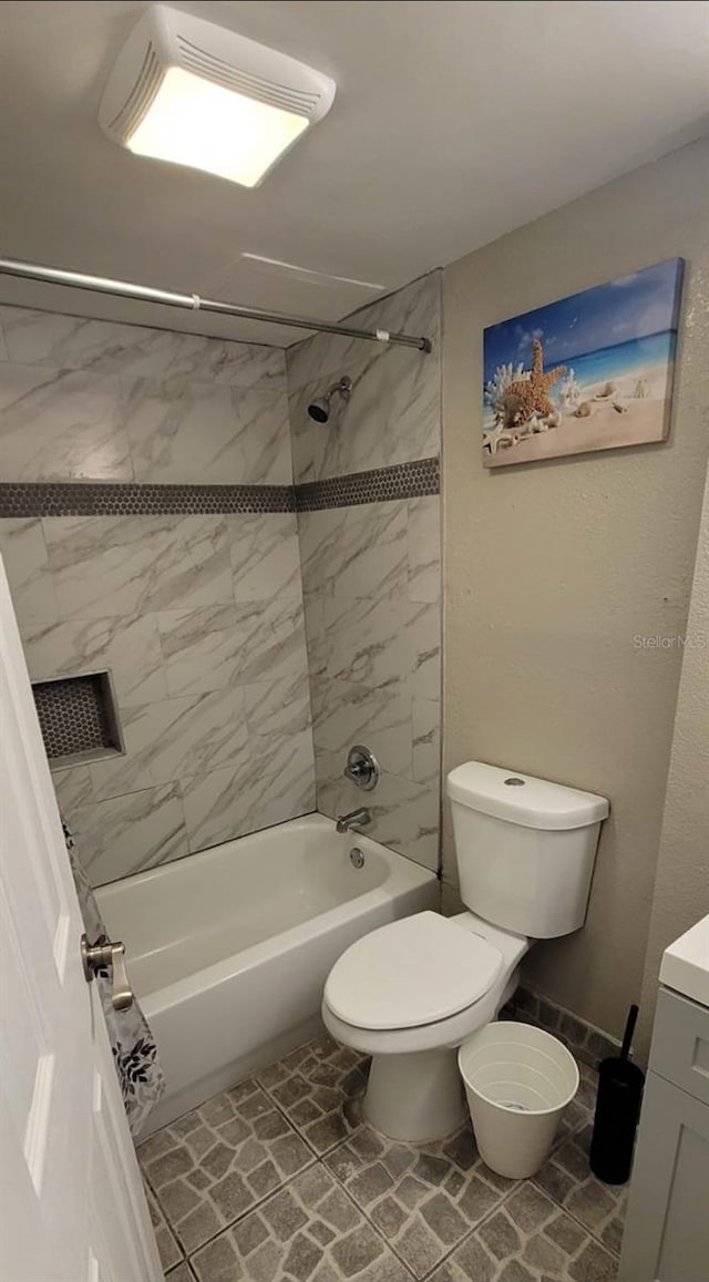 full bathroom featuring vanity, tiled shower / bath, tile patterned flooring, and toilet