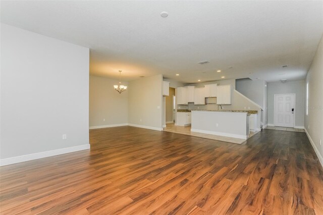 unfurnished living room featuring wood-type flooring and a notable chandelier