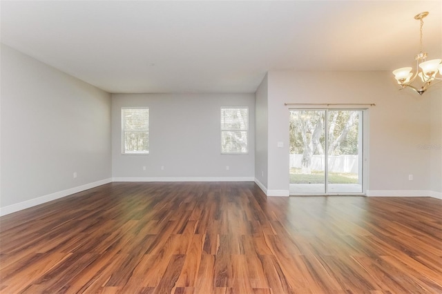 unfurnished room featuring dark wood-type flooring and a notable chandelier