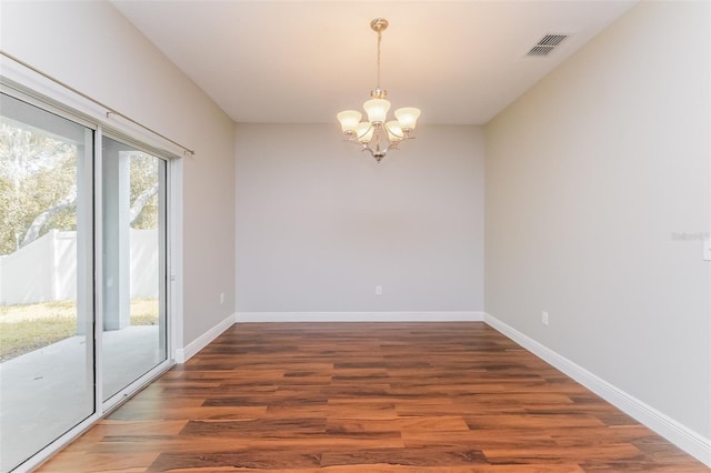 spare room featuring dark hardwood / wood-style floors and an inviting chandelier