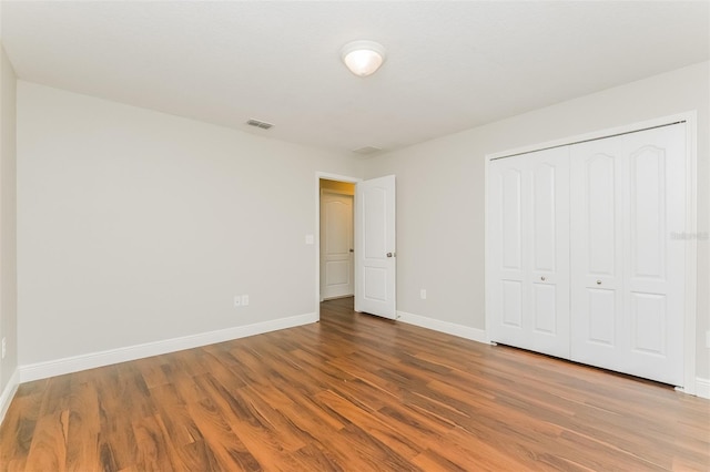 unfurnished bedroom with a closet and hardwood / wood-style floors