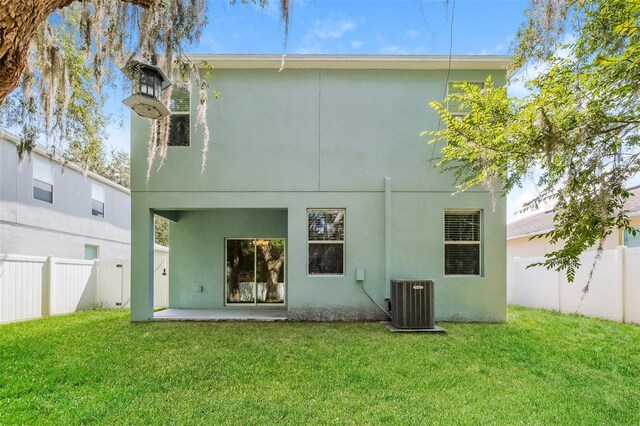 rear view of house with central air condition unit and a yard