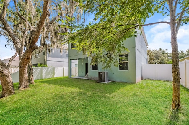 rear view of house with central AC and a lawn