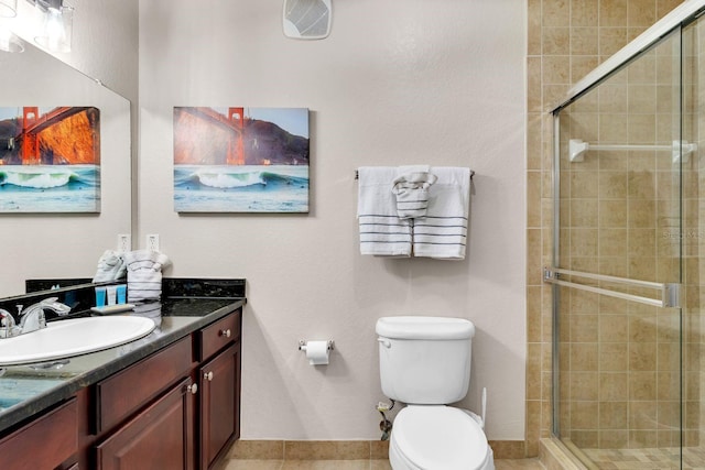 bathroom featuring a shower with shower door, vanity, tile patterned flooring, and toilet