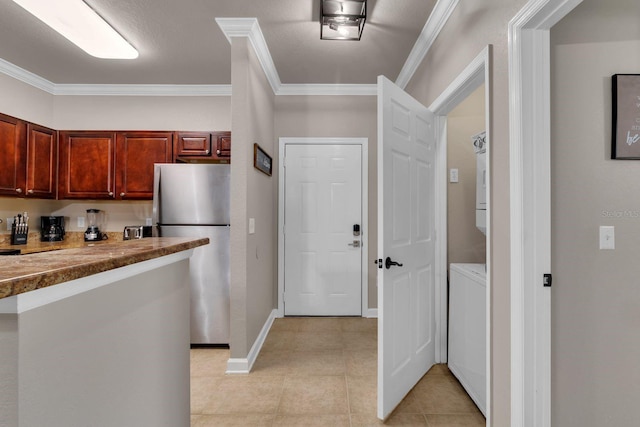 kitchen featuring light tile patterned floors, stacked washer and clothes dryer, stainless steel fridge, and crown molding