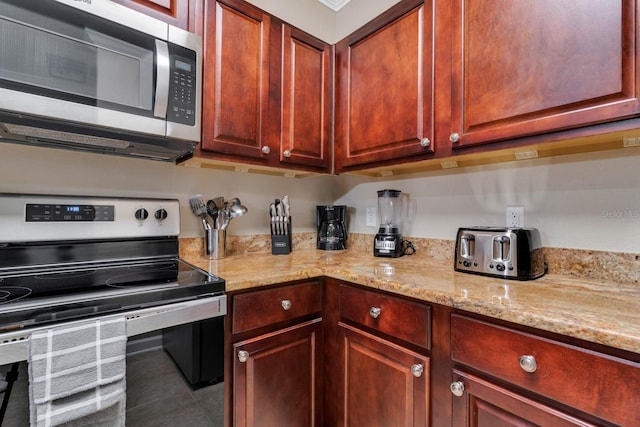 kitchen with appliances with stainless steel finishes, tile patterned flooring, and light stone countertops